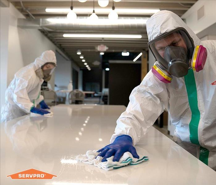 image of person in full PPE sanitizing table for coronavirus
